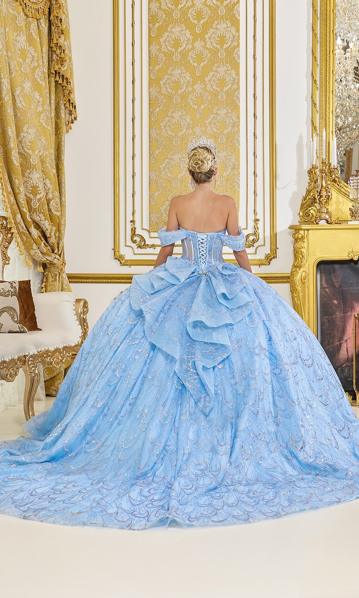 A woman wearing the Quinceanera Dress 5076 by Dancing Queen stands with her back to the camera in a lavish, gold-accented room.